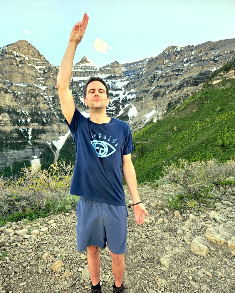 Jess with one arm raised overhead in a protection posture, high on a ridge below Mount Timpanogos.